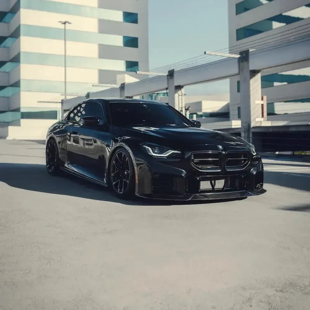 Black BMW G87 M2 with carbon fiber front kidney grilles, outdoor photo (AN Style)