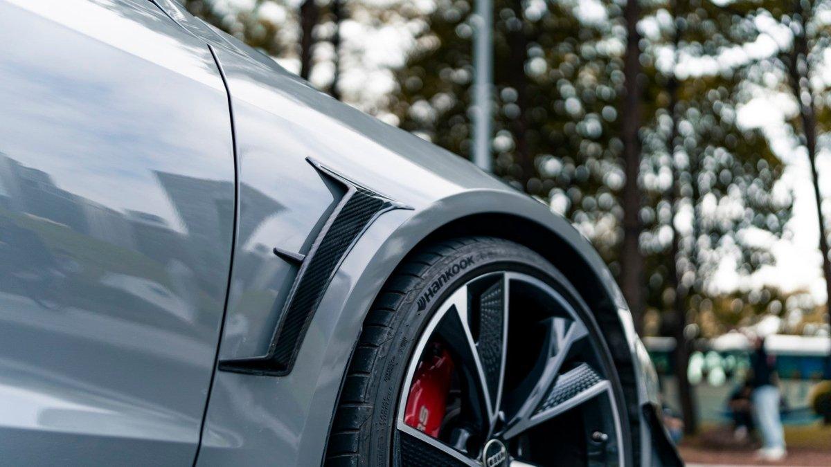Sarló alakú carbon sárvédő díszléc egy szürke C8 bal első sárvédőjén, szabadtéren (KB Style) – Audi RS6 Avant C8