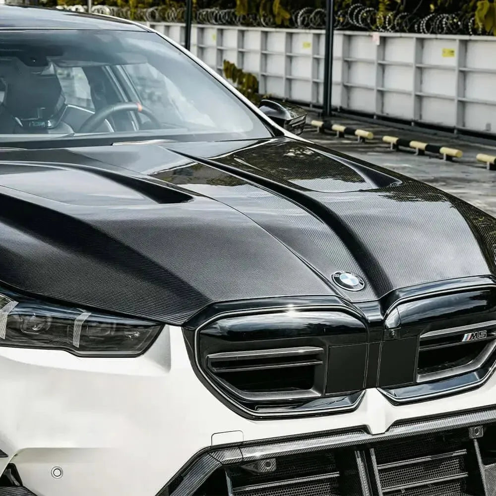 Vented carbon fiber hood (SQ Style) on a white BMW G90 M5, front three-quarter close-up