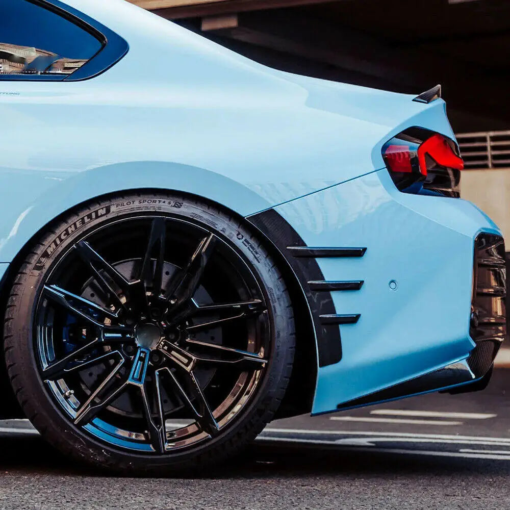 Light kék bmw g87 m2 kerékív sárvédő betét carbon fiber anyagból fekete alufelnikkel és piros hátsó lámpákkal hátulról nézve