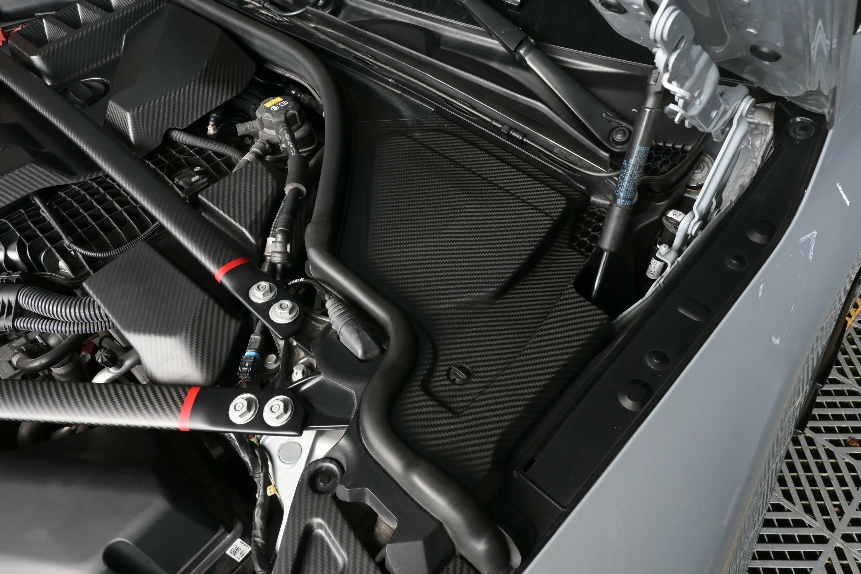 Fekete carbon fiber motortér burkolat texturált szövettel és precíz kivágásokkal bmw m3 kipufogó rendszerhez
