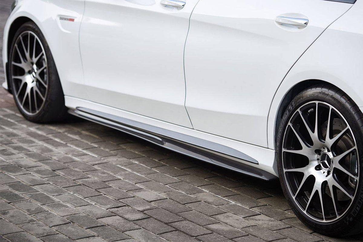Fehér Mercedes-AMG C63 W205 oldalnézetből, felszerelt carbon oldalsó szoknya toldattal, macskakövön (PS Style)
