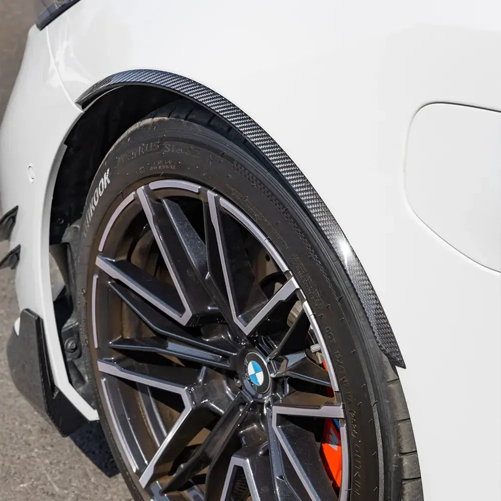 Close-up of a white BMW G90 M5 front wheel arch, with fitted carbon wheel arch trim