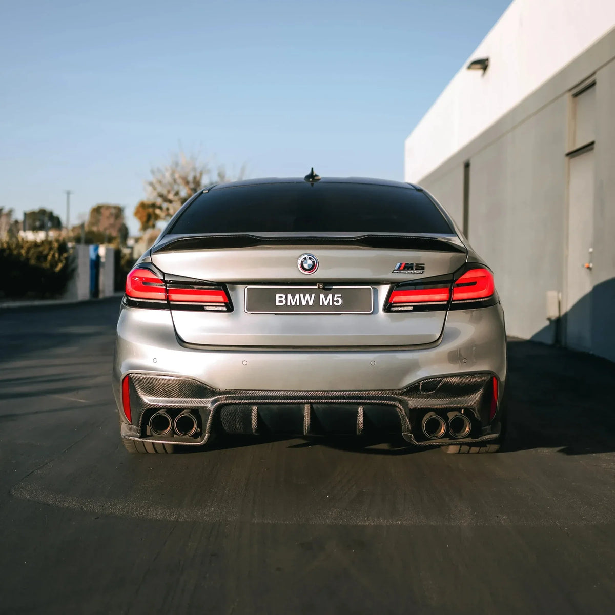 Gray LCI BMW F90 M5, rear view, with fitted carbon trunk spoiler (MP PRO V1 Style)