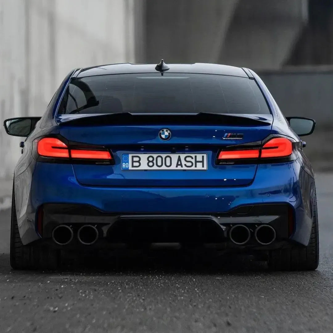 Blue LCI BMW F90 M5 straight from behind, with raised carbon trunk spoiler (PSM Style High Kick)