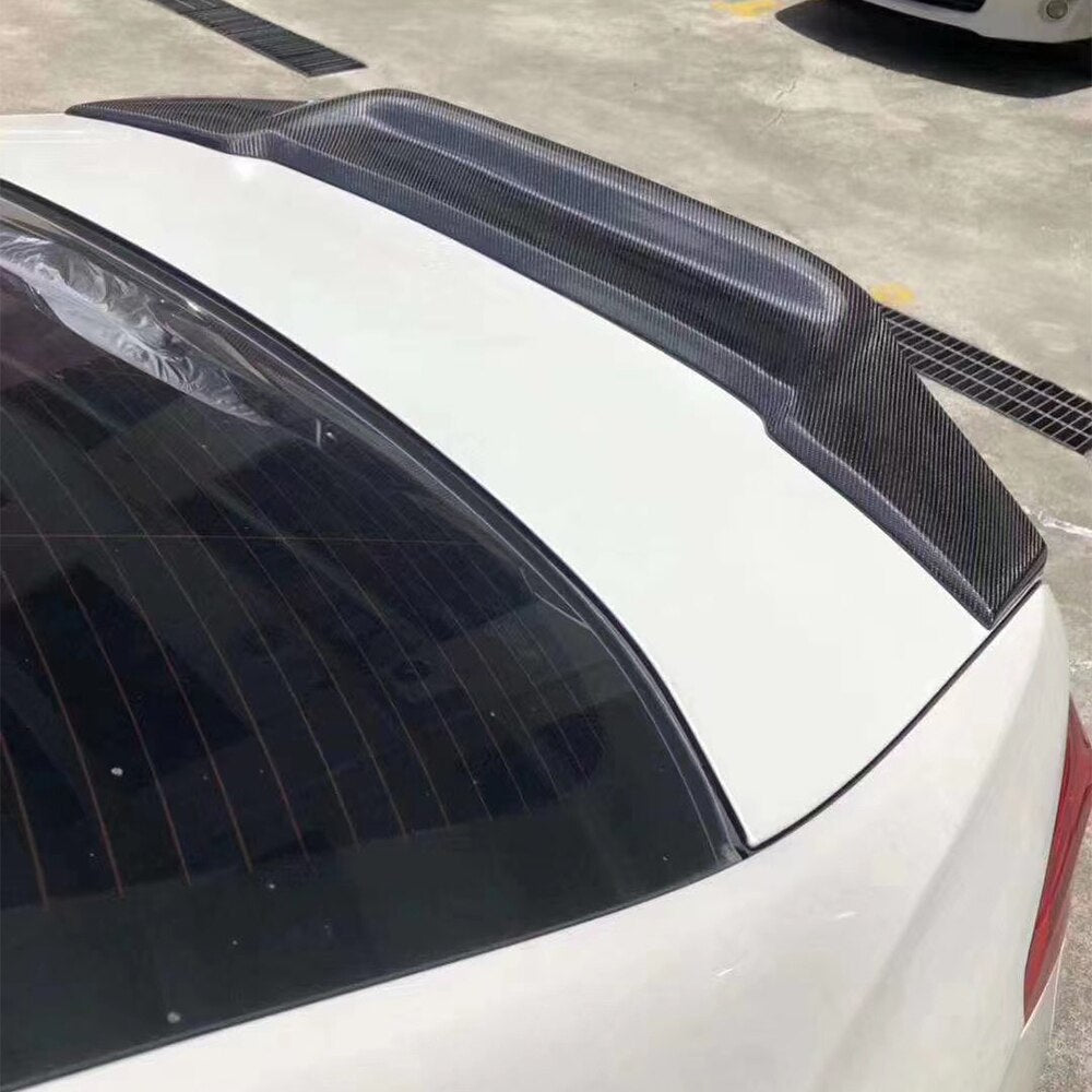 White BMW G30 trunk from above, with raised carbon ducktail spoiler (R Style)