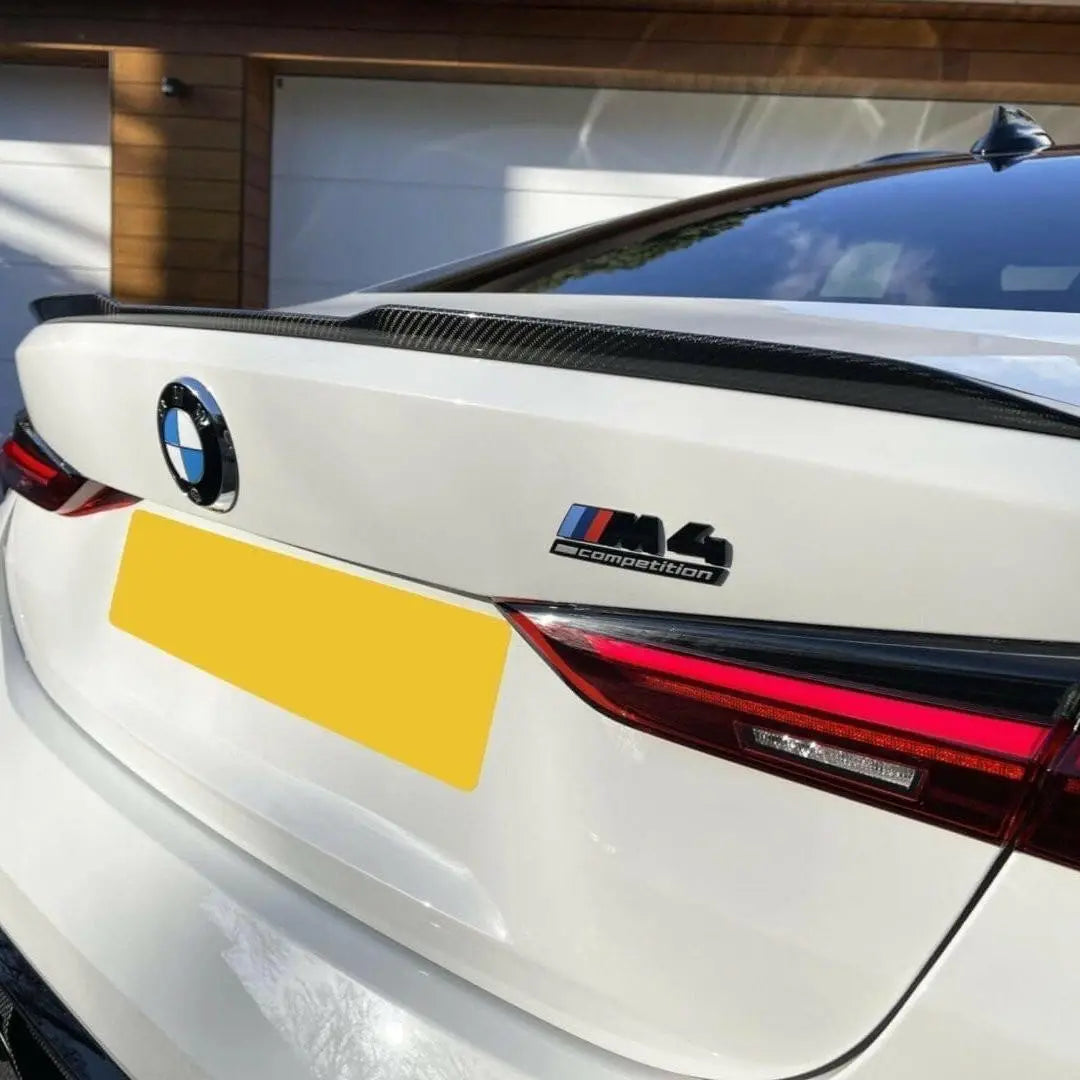 Hátsó nézet fehér bmw m4 competition szárny carbon fiber trimmel és fényes felülettel a kipufogó rendszerhez