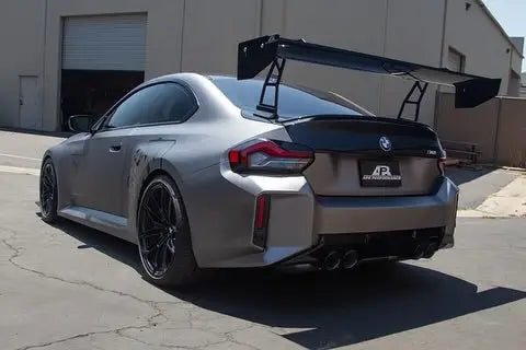 Ezüst matt felületű bmw m2 fekete hátsó szárnnyal és carbon fiber kipufogó rendszerrel a hátulról