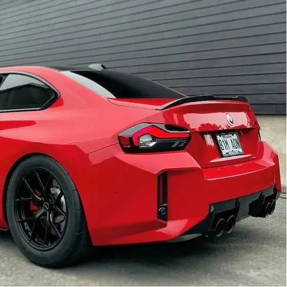 Vibráló piros bmw m2 karbon szárnyak sportos hátsó spoilerrel és fekete felnik kipufogó rendszerhez