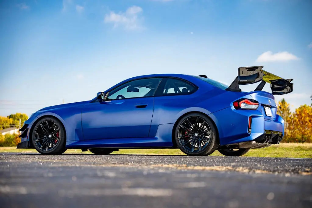 Vibráló kék bmw m2 cs fekete karbon szárnyakkal és kipufogó rendszerrel hátulról szárnyak carbon fiber bmw g87 m2