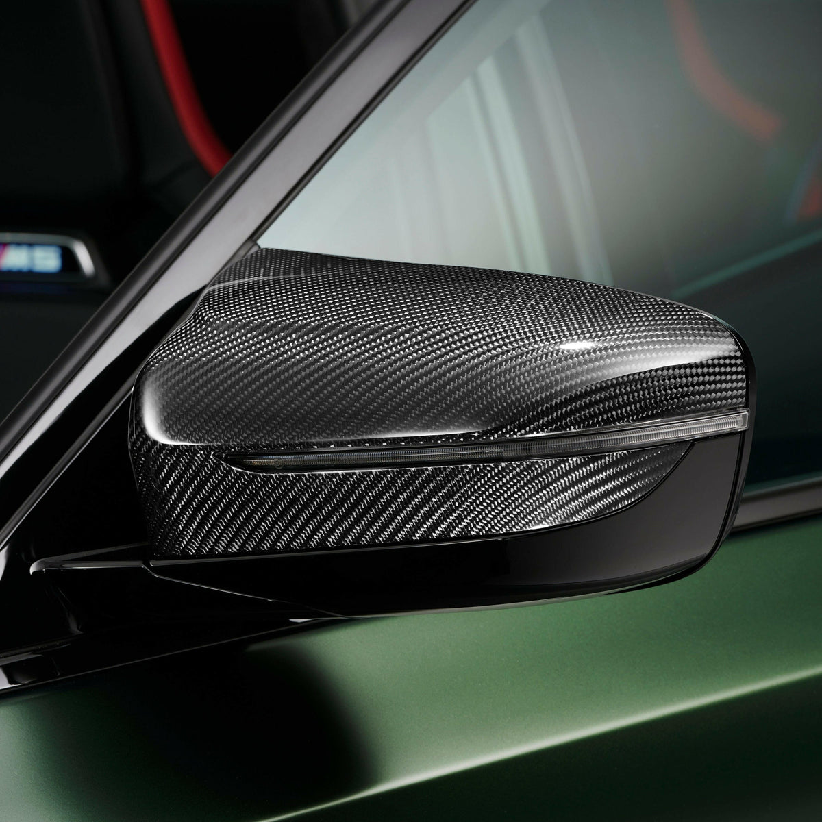 Close-up of a dark green BMW F90 M5 CS carbon mirror cap