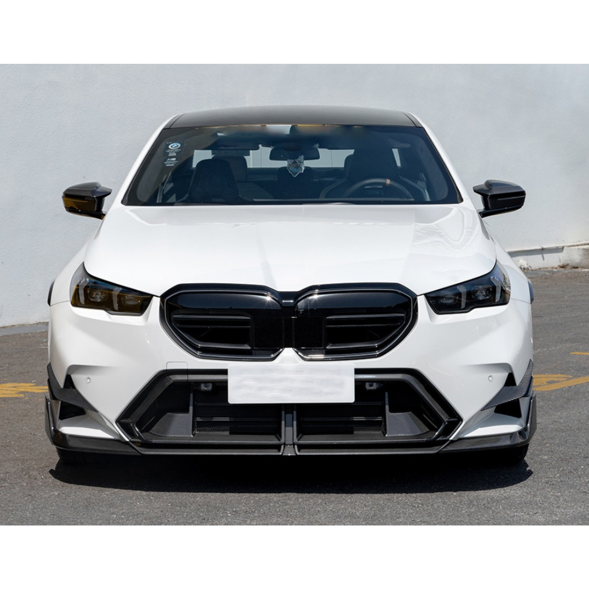 Fehér BMW G90 M5 elölnézetből, fekete carbon tükörborításokkal (M Style)